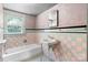 This bathroom features vintage, pink and gray ceramic tiling and a large window for natural light at 1520 21St Ne Ave, Hickory, NC 28601
