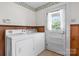 Bright laundry room with white washer and dryer, featuring a window for natural light and wood paneling at 1520 21St Ne Ave, Hickory, NC 28601