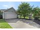 View of the house's garage with a basketball hoop, a driveway, and mature landscaping behind a fence at 17327 Summers Walk Blvd, Davidson, NC 28036