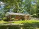 Rear exterior view of a brick home featuring a ramp and access to a well-shaded yard surrounded by trees at 2120 Marwood Ln, Albemarle, NC 28001