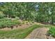Professionally landscaped backyard with mature trees, shrubs, and a stone pathway leading to upper level at 2317 Houston Branch Rd, Charlotte, NC 28270