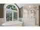 Luxurious bathroom featuring a modern tub, frameless glass shower, and shuttered arched window at 2317 Houston Branch Rd, Charlotte, NC 28270