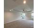 Spacious carpeted bedroom featuring a tray ceiling, ceiling fan, and multiple windows at 2382 Drake Mill Sw Ln, Concord, NC 28025