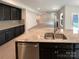 Kitchen island with granite countertop, stainless steel sink, and a view into the open-concept living space at 2382 Drake Mill Sw Ln, Concord, NC 28025