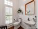 Elegant powder room featuring a pedestal sink, plantation shutters, and a decorative mirror at 3036 Luke Crossing Dr, Charlotte, NC 28226