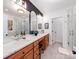Modern bathroom with wood cabinets, white marble countertop, decorative mirror, and glass enclosed shower at 3036 Luke Crossing Dr, Charlotte, NC 28226
