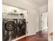 Laundry room with modern washer and dryer set, overhead shelving, and hardwood floors at 3036 Luke Crossing Dr, Charlotte, NC 28226