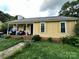 Quaint yellow home featuring a covered porch with storage and a small front yard at 3396 Farm Lake Sw Dr, Concord, NC 28027