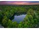 Picturesque aerial view of a wooded property featuring a serene lake surrounded by lush greenery at 408 Covington Xing, Matthews, NC 28104