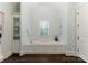 Bright bathroom featuring a soaking tub with tile surround and a window, creating a tranquil spa-like experience at 408 Covington Xing, Matthews, NC 28104