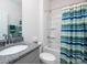 Modern bathroom with granite vanity, toilet, and shower-tub with blue and green striped shower curtain at 4177 Steel Way, Sherrills Ford, NC 28673