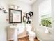 Bathroom features a pedestal sink, decorative mirror, toilet, and a window with natural light at 4312 Mary Point Rd, Monroe, NC 28110