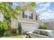 View of tan two-story home with attached garage, greenery, and a neutral car parked on the driveway at 4312 Mary Point Rd, Monroe, NC 28110