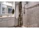 Tiled bathroom features a shower with decorative tile accents and a vanity with framed mirror and elegant lighting at 5014 Quail Canyon Dr, Charlotte, NC 28226