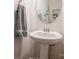 Elegant powder room featuring a pedestal sink, framed mirror, and soft gray towel at 5391 Orchid Bloom Dr, Indian Land, SC 29707