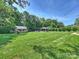 Expansive backyard with manicured lawn, gazebo with patio, string lights, and mature trees for privacy at 5921 Meadowmere Dr, Monroe, NC 28110