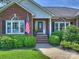 Beautiful brick home entrance with manicured bushes, arched windows, and an American flag at 5921 Meadowmere Dr, Monroe, NC 28110