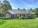 Charming brick home with manicured lawn, mature trees, and an American flag at 5921 Meadowmere Dr, Monroe, NC 28110