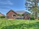 Brick home exterior showcasing the back deck with outdoor seating, a well-manicured lawn, and mature trees at 5921 Meadowmere Dr, Monroe, NC 28110