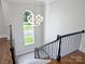 Elegant staircase with dark wood railing, modern light fixture, and large window at 6314 Saint Stephen Ln, Charlotte, NC 28210