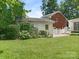 Spacious backyard showcasing green lawn, mature trees, and a detached garage for parking or storage at 7118 Powder Mill Pl, Charlotte, NC 28277