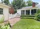 Well-maintained backyard showcasing lush green lawn, brick pathway, and a cozy sunroom addition at 7118 Powder Mill Pl, Charlotte, NC 28277