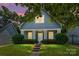Charming home featuring a covered porch and landscaped front yard with manicured shrubbery at night at 1226 Rising Oak Dr, Charlotte, NC 28206