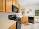 Functional kitchen with light wood cabinets, black appliances, and a garden window over the sink at 12415 Stratfield Place Cir, Pineville, NC 28134