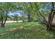 View of a large backyard featuring mature trees providing ample shade and greenery at 13909 Idlewild Rd, Matthews, NC 28105