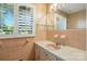 Well-lit bathroom featuring a vanity sink, mirror, and window with patterned window treatment at 13909 Idlewild Rd, Matthews, NC 28105