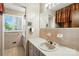 Well-lit bathroom featuring a vanity sink, mirror, and window with patterned window treatment at 13909 Idlewild Rd, Matthews, NC 28105