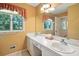 Bright bathroom featuring a double sink vanity, mirror, and large window with natural light at 13909 Idlewild Rd, Matthews, NC 28105