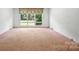 Cozy bedroom featuring carpeted floors and a large window offering natural light, a perfect private retreat at 13909 Idlewild Rd, Matthews, NC 28105