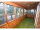 Enclosed sunroom showcasing wood paneled walls, multiple windows, and green carpeting at 1409 Turner Dr, Gastonia, NC 28052