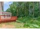 View of the backyard featuring a wood deck, green grass and a dense treeline at 14333 Maclauren Ln, Huntersville, NC 28078