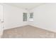 Bright carpeted bedroom featuring two windows and neutral walls, offering a versatile space at 14333 Maclauren Ln, Huntersville, NC 28078