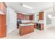 Well-lit kitchen featuring wooden cabinets, stainless steel appliances, a kitchen island, and tile flooring offers ample workspace at 14333 Maclauren Ln, Huntersville, NC 28078