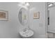 Elegant half bath with pedestal sink, oval mirror, and coastal-themed decor at 1527 Scarbrough Sw Cir, Concord, NC 28025