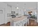 This is a modern kitchen with an island and stools, with stainless steel appliances and an open concept to the living room at 1527 Scarbrough Sw Cir, Concord, NC 28025
