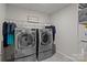 Modern laundry room equipped with two front-load washing machines and shelving for storage at 169 Rooster Tail Ln, Troutman, NC 28166