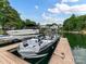 Several boats docked on a peaceful lake with lush greenery and beautiful waterfront homes in the background at 19205 Hidden Cove Ln, Cornelius, NC 28031