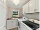 Bright laundry room featuring modern washer and dryer, wood countertop, white cabinets, and stylish overhead lighting at 19205 Hidden Cove Ln, Cornelius, NC 28031