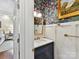 Stylish powder room with a floral wallpaper accent wall, wainscoting, and a marble countertop vanity at 19205 Hidden Cove Ln, Cornelius, NC 28031