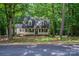 Charming two-story home with a inviting front porch and dormer windows nestled among mature trees at 203 Hickory Wood Dr, Kannapolis, NC 28083