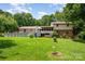 Backyard view featuring green grass, above ground pool, deck and swing, and mature trees for outdoor enjoyment at 2109 Quail Nw Dr, Concord, NC 28027
