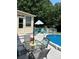 Inviting pool deck with a glass table, gray chairs, Adirondack chairs, and an umbrella for comfortable outdoor entertaining at 2109 Quail Nw Dr, Concord, NC 28027