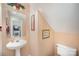 Powder room featuring a pedestal sink, toilet, framed mirror, and peach paint at 220 Holmes Ct, Concord, NC 28027