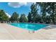 Community swimming pool with lounge chairs, tables, umbrellas, and landscaped greenery at 220 Holmes Ct, Concord, NC 28027