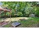 Large, tree-filled backyard featuring a fire pit, shed, and rustic deck at 220 Plonk Rd, Dallas, NC 28034
