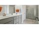 Bathroom featuring gray cabinets, double sinks, a vanity mirror, and a tiled walk in shower with a glass door at 3256 Fairmead Dr, Concord, NC 28025